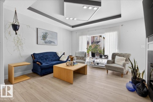 Living room featuring light-colored flooring, a tray ceiling with integrated lighting, and a large sliding glass door - 1778 25A Street, Edmonton, AB - Indoor Photo Showing Living Room