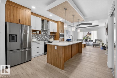 The kitchen features a stainless steel refrigerator, a white countertop island, and light wood-style flooring - 1778 25A Street, Edmonton, AB - Indoor Photo Showing Kitchen With Upgraded Kitchen
