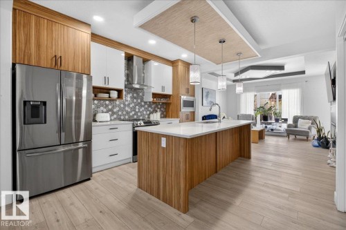 The kitchen features stainless steel appliances, a large island with a white countertop, and a tiled backsplash - 1778 25A Street, Edmonton, AB - Indoor Photo Showing Kitchen With Upgraded Kitchen