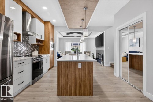 The kitchen features a large island with a white countertop and pendant lighting, stainless steel appliances, and a mosaic tile backsplash - 1778 25A Street, Edmonton, AB - Indoor Photo Showing Kitchen With Upgraded Kitchen