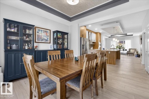 The property features light-toned hardwood flooring throughout, extending from the dining area to the kitchen and living area - 1778 25A Street, Edmonton, AB - Indoor Photo Showing Dining Room