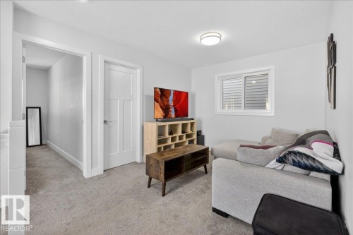 This inviting room features soft gray carpeting, white walls, and a window with blinds providing natural light - 1778 25A Street, Edmonton, AB - Indoor
