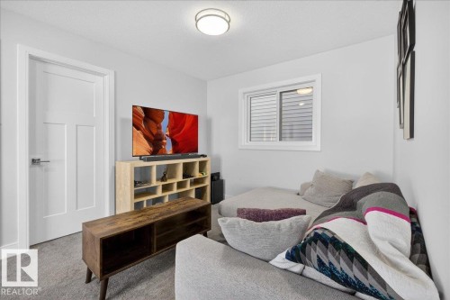 A cozy living space featuring a window with blinds, a modern ceiling light fixture, and light-colored walls - 1778 25A Street, Edmonton, AB - Indoor