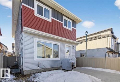 The property features a two-story exterior with light blue and red siding, white window frames, and a private driveway - 1778 25A Street, Edmonton, AB - Outdoor With Exterior