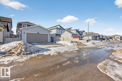 The property features a light grey exterior and an attached garage with a large driveway - 1778 25A Street, Edmonton, AB - Outdoor