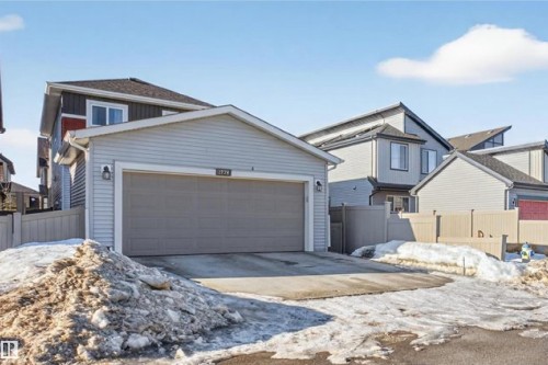 The property features a detached garage with an overhead door, complemented by light-colored siding and an exterior light fixture - 1778 25A Street, Edmonton, AB - Outdoor