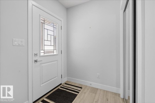 Entryway featuring a white door with decorative glass inserts, light wood-style flooring, and a white baseboard trim - 1778 25A Street, Edmonton, AB - Indoor Photo Showing Other Room