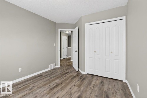 Unfurnished bedroom featuring a textured ceiling, a closet, and wood finished floors - 150 Acacia Circle, Leduc, AB - Indoor