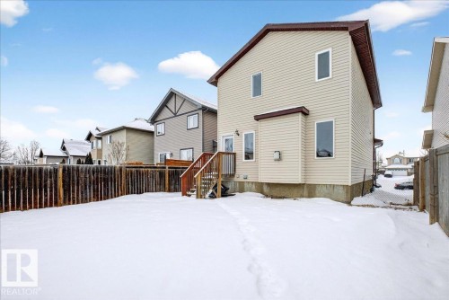 Snow covered rear of property with a fenced backyard and a deck - 150 Acacia Circle, Leduc, AB - Outdoor With Exterior