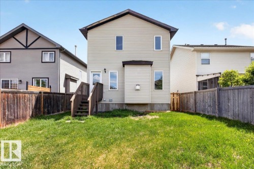 Rear exterior with light-colored siding, a wooden staircase leading to an upper-level door, and a grassy lawn - 150 Acacia Circle, Leduc, AB - Outdoor With Exterior