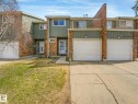 Townhome exterior featuring brick and vertical siding, attached garage, concrete driveway, and front entryway - 13405 40 St Nw, Edmonton, AB  - Outdoor 