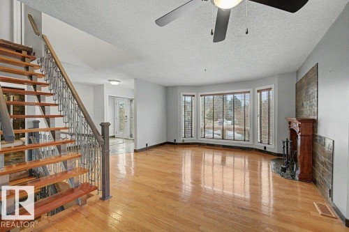 Living room with hardwood floors, a bay window, and a fireplace with a wood mantle and stone surround - Edmonton, AB - Indoor Photo Showing Other Room
