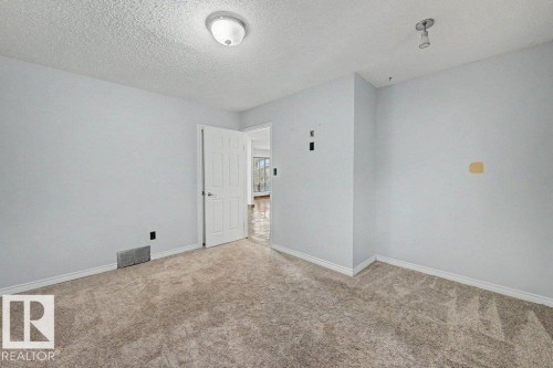Room featuring light-colored walls, textured carpeting, and a white interior door - Edmonton, AB - Indoor Photo Showing Other Room