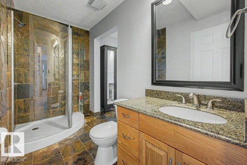 The bathroom features a walk-in shower with a glass enclosure, a vanity with a granite countertop, and a framed mirror - Edmonton, AB - Indoor Photo Showing Bathroom