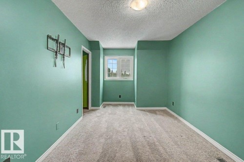 This room features light-colored carpet, a window, and a door frame - Edmonton, AB - Indoor Photo Showing Other Room