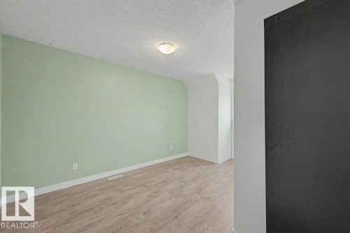 The property features light wood-style flooring, light green walls, and white trim throughout the space - Edmonton, AB - Indoor Photo Showing Other Room