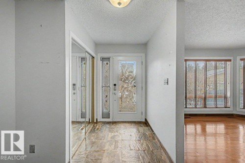 Entryway featuring a decorative glass front door, mirrored closet doors, and tile flooring - Edmonton, AB - Indoor Photo Showing Other Room