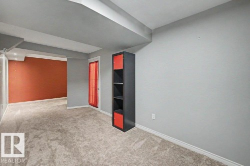 This interior space features light-colored carpeting throughout, gray walls, and a contrasting accent wall in a deep orange hue - Edmonton, AB - Indoor Photo Showing Other Room