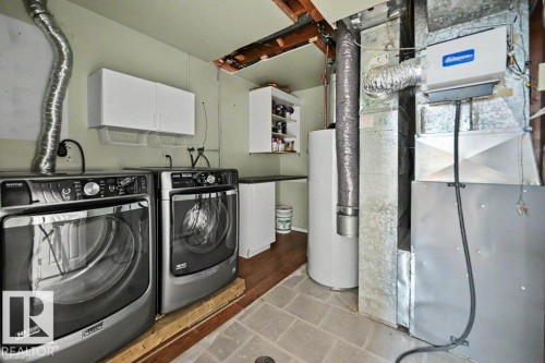 The property includes a dedicated laundry area with white cabinetry, a built-in countertop, and a water heater - Edmonton, AB - Indoor Photo Showing Laundry Room