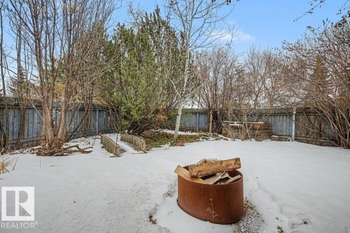 The property features a fenced yard with a fire pit, a small wooden bridge, and a mix of deciduous and evergreen trees - Edmonton, AB - Outdoor