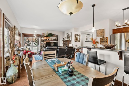 Open-concept dining area featuring wood-finish flooring, a contemporary ceiling light fixture, and a pass-through bar - 2201 Graybriar Green, Stony Plain, AB - Indoor Photo Showing Dining Room