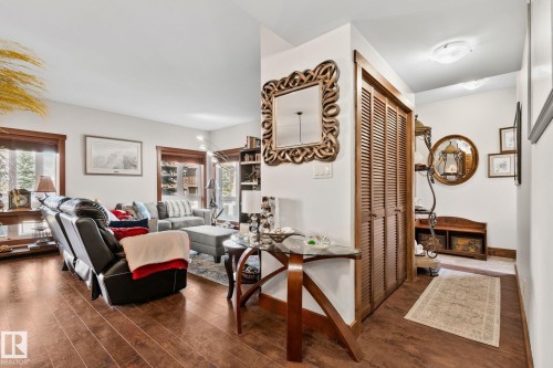 Laminate wood-finish flooring extending into the living area, featuring white walls, and wood-trimmed windows providing natural light - 2201 Graybriar Green, Stony Plain, AB - Indoor Photo Showing Other Room
