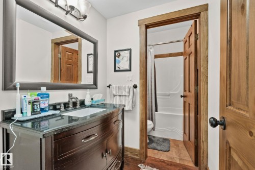 Bathroom vanity featuring a dark wood finish, a black countertop, and an undermount sink with a chrome faucet - 2201 Graybriar Green, Stony Plain, AB - Indoor Photo Showing Bathroom