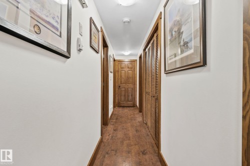 Hallway featuring wood-finish flooring, wood trim, flush-mount lighting, and bi-fold louvered doors - 2201 Graybriar Green, Stony Plain, AB - Indoor Photo Showing Other Room