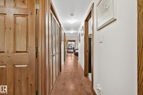 Hallway featuring wood-finish flooring, light wood panel doors, louvered closet doors, and recessed lighting - 2201 Graybriar Green, Stony Plain, AB - Indoor Photo Showing Other Room