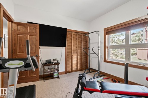 Room featuring textured carpeting, a wood-paneled door, and louvered bifold closet doors - 2201 Graybriar Green, Stony Plain, AB - Indoor