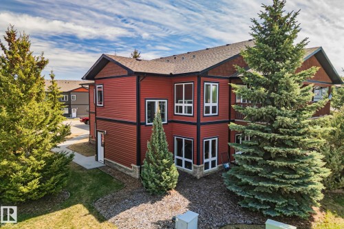 Two-story exterior featuring red siding with dark trim, multiple large windows, and a prominent balcony - 2201 Graybriar Green, Stony Plain, AB - Outdoor