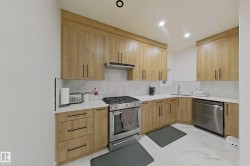 Modern kitchen featuring wood-finish cabinetry, white countertops, a tiled backsplash, stainless steel appliances, and recessed lighting - 