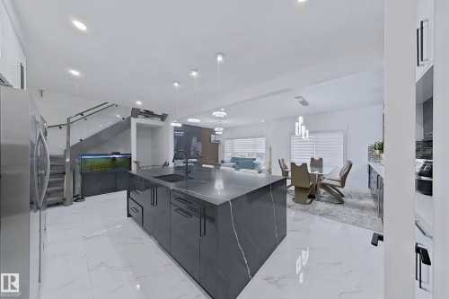 Kitchen island with dark stone countertop and waterfall edge, featuring an integrated sink and modern black faucet - 1210 Peregrine Terrace, Edmonton, AB - Indoor Photo Showing Other Room