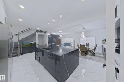 Kitchen island with dark stone countertop and waterfall edge, featuring an integrated sink and modern black faucet - 