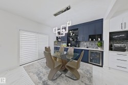 Integrated dining area featuring a modern geometric chandelier over a glass-top table - 