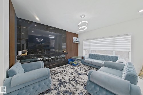 Contemporary living space featuring a floor-to-ceiling accent wall with a large built-in media center and linear electric fireplace - 1210 Peregrine Terrace, Edmonton, AB - Indoor