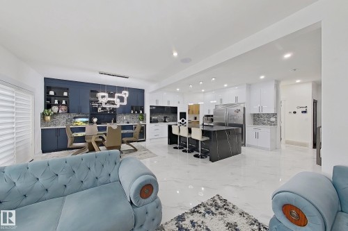 Open-concept living space featuring a modern kitchen with a waterfall island, stainless steel appliances, and white cabinetry - 1210 Peregrine Terrace, Edmonton, AB - Indoor