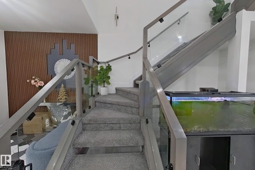 Modern staircase featuring glass panel railings with metal posts and handrails - 1210 Peregrine Terrace, Edmonton, AB - Indoor Photo Showing Other Room