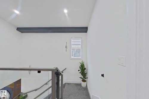 Modern staircase featuring glass panel railings, sleek metal newel posts, and a dark accent beam - 1210 Peregrine Terrace, Edmonton, AB - Indoor Photo Showing Other Room