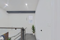Modern staircase featuring glass panel railings, sleek metal newel posts, and a dark accent beam - 