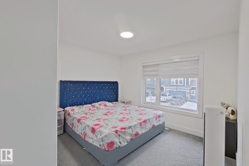 Room featuring a large window with privacy blinds, light gray carpet flooring, white walls, and a recessed ceiling light fixture - 1210 Peregrine Terrace, Edmonton, AB - Indoor Photo Showing Bedroom