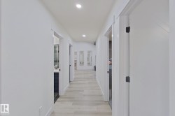 Hallway featuring recessed lighting, light wood-finish flooring, white walls, and white trim - 