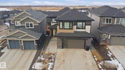 Contemporary two-story residence featuring a two-car garage with modern frosted glass panels and stone accents - 
