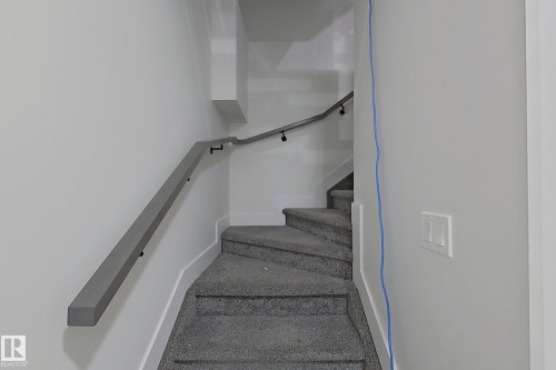 Carpeted staircase with contemporary grey wall-mounted handrail, recessed wall lighting, and white baseboards - 1210 Peregrine Terrace, Edmonton, AB - Indoor Photo Showing Other Room