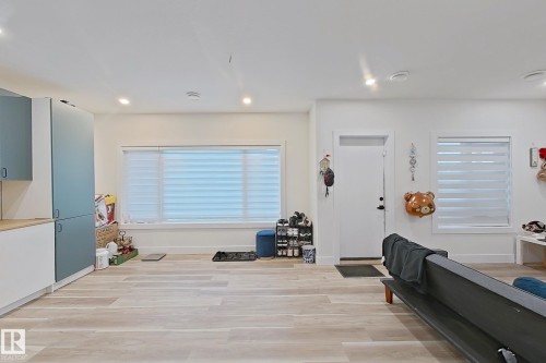 Open-concept living area featuring light wood-finish flooring, recessed lighting, and expansive windows with horizontal blinds - 1210 Peregrine Terrace, Edmonton, AB - Indoor
