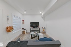 Living area with recessed lighting, light wood-finish flooring, and white walls - 