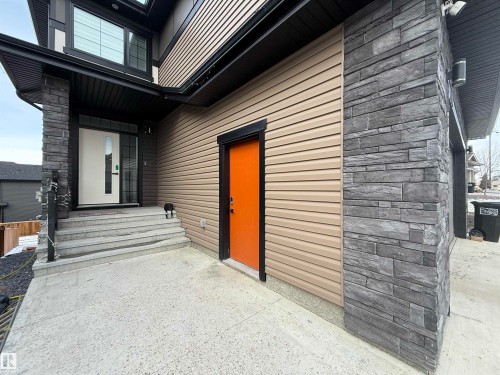 Contemporary exterior featuring horizontal siding in a neutral tone, complemented by dark stacked stone accents - 1210 Peregrine Terrace, Edmonton, AB - Outdoor With Exterior