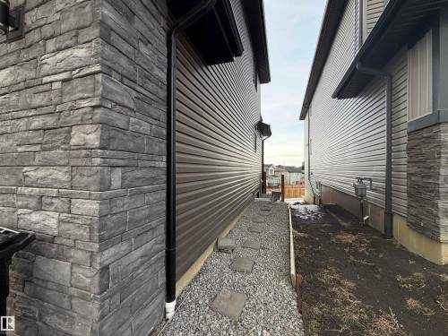Exterior wall featuring stacked stone veneer and horizontal siding - 1210 Peregrine Terrace, Edmonton, AB - Outdoor