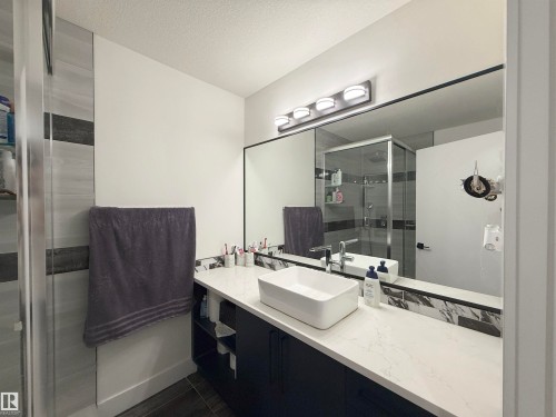 Modern bathroom featuring a rectangular vessel sink, white countertop, dark wood-finish vanity, and a large wall-mounted mirror - 1210 Peregrine Terrace, Edmonton, AB - Indoor Photo Showing Bathroom