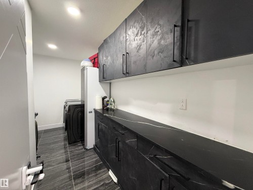 Utility room featuring dark marble-look countertops and extensive cabinetry with dark hardware - 1210 Peregrine Terrace, Edmonton, AB - Indoor Photo Showing Other Room